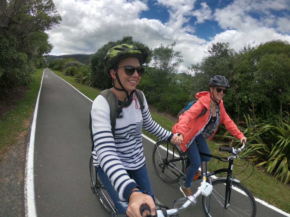 dos chicas cogidas de la mano y montadas en una bicicleta